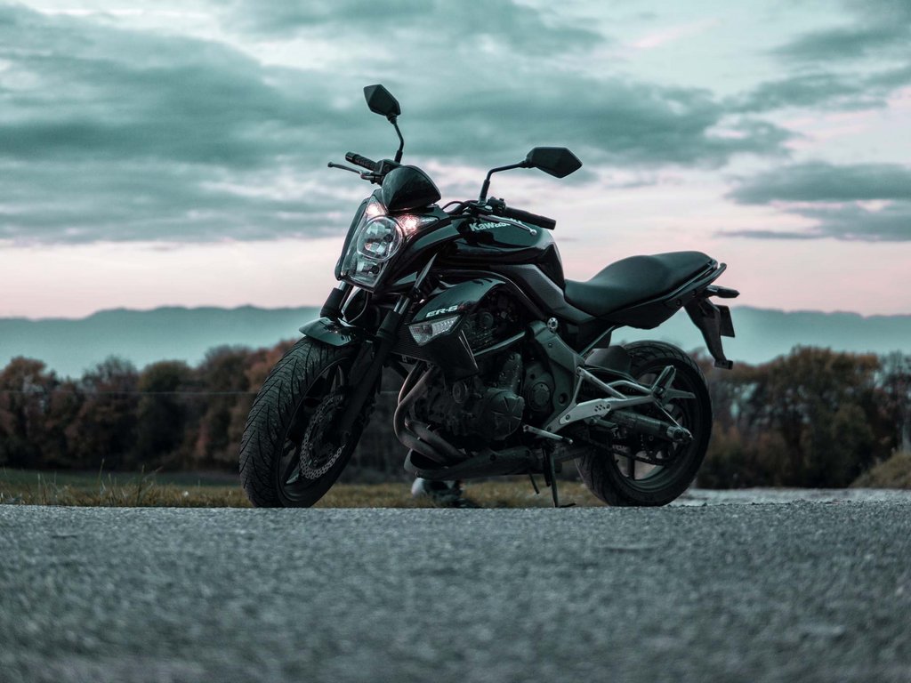 Noleggio bici a Soraga: un must in autunno all’Hotel Latemar Moto Kawasaki nera parcheggiata su strada con cielo nuvoloso sullo sfondo