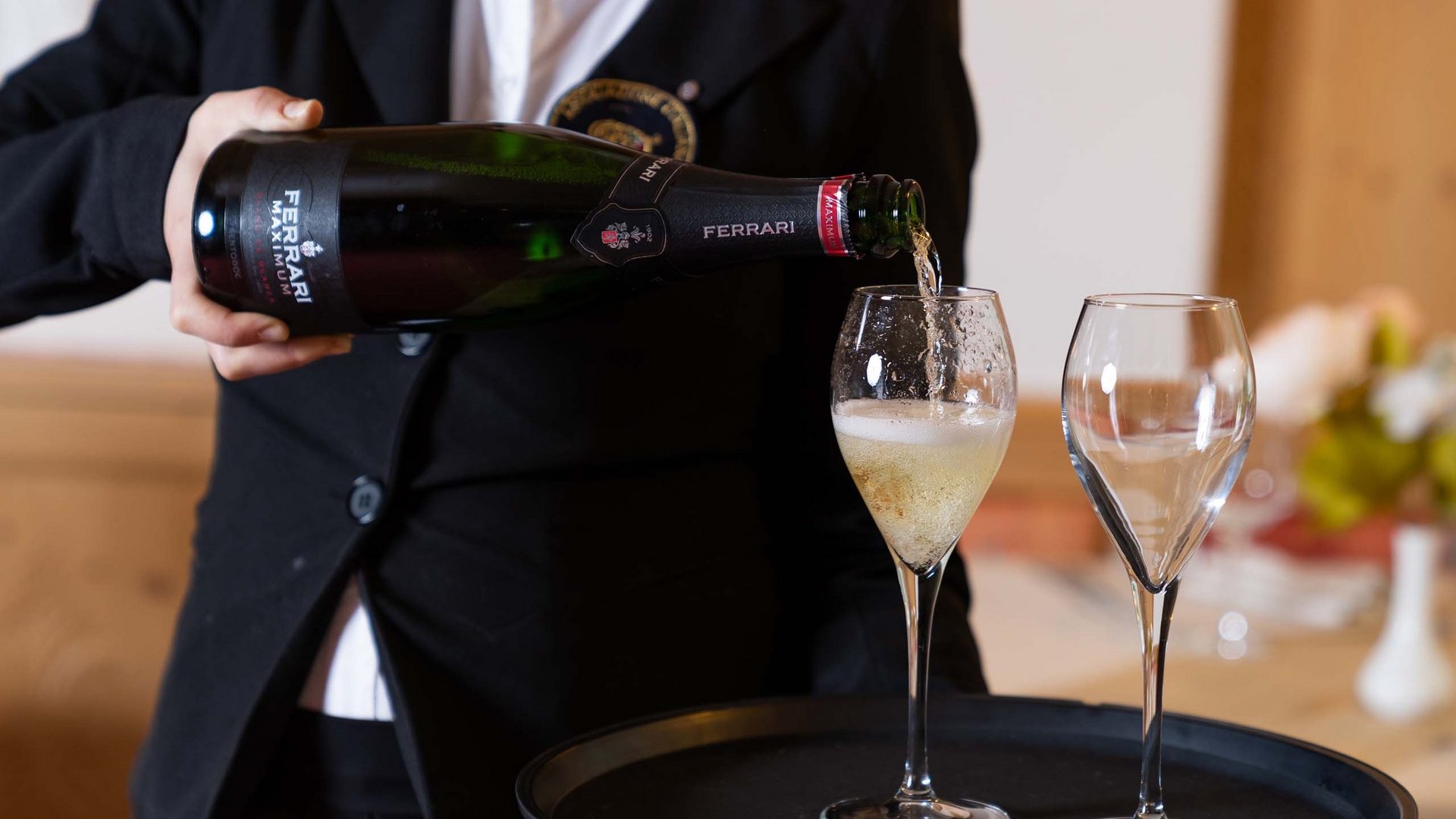 In Val di Fassa in inverno e in estate si brinda col vino! Cameriere versa spumante Ferrari in un calice da degustazione