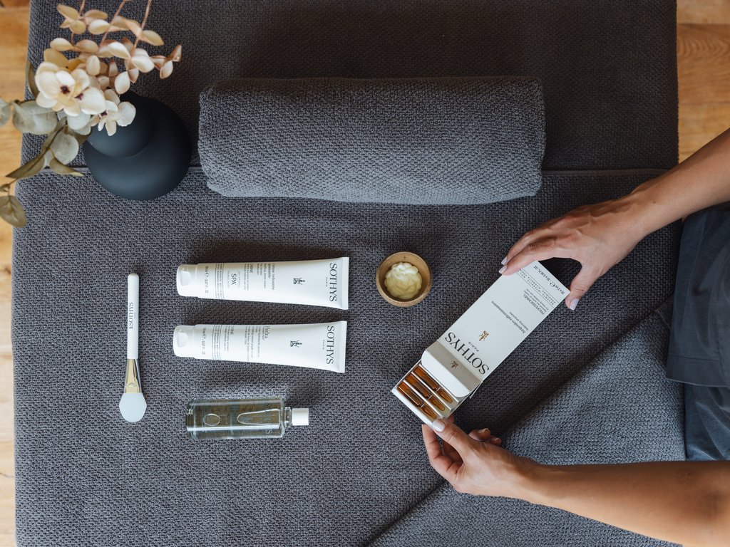 A Soraga il meteo è sempre ottimo per un Day Spa! Prodotti Sothys per trattamento spa su asciugamano grigio con mani di donna