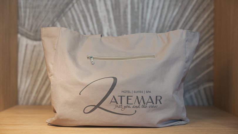 Moena, alberghi da sogno, panorama? C’è l’Hotel Latemar! Borsa beige con logo Latemar posata su una mensola di legno