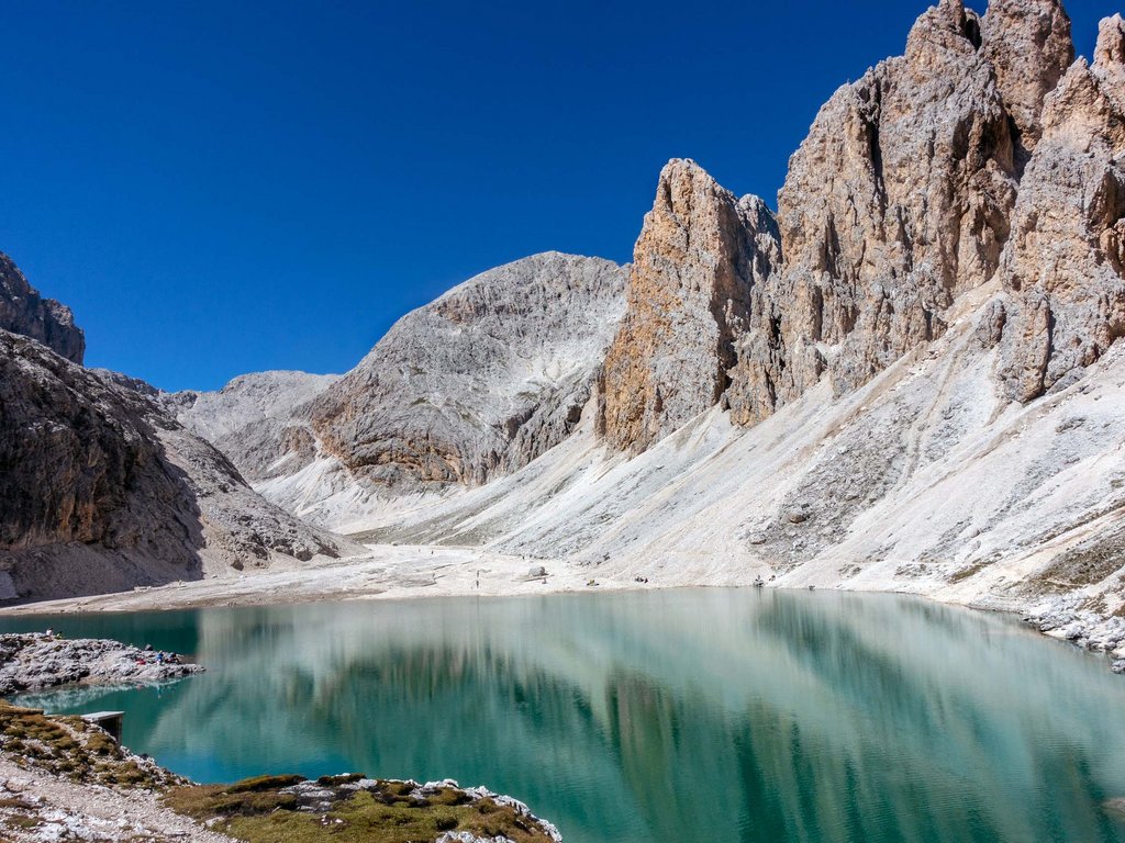 Lago di Soraga e attività estive vicino al Latemar Lago alpino tranquillo circondato da montagne rocciose sotto un cielo azzurro