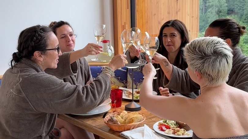 A Soraga il meteo è sempre ottimo per un Day Spa! Gruppo di persone in accappatoi che brindano a tavola con cibo e pane