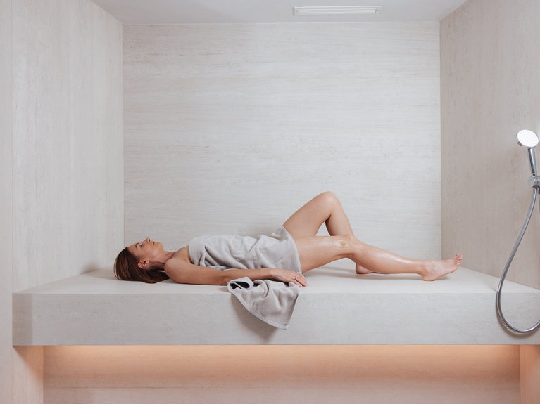 Il rituale dell’hammam al Latemar Hotel Donna distesa su panca in ambiente bagno moderno con doccetta a parete