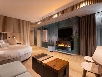 Hotel a 3 stelle superior a Soraga in Val di Fassa: camere & suites Camera d'albergo moderna con letto rotondo, camino elettrico e mobili in legno