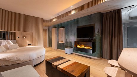 Meteo, Moena, Soraga, Latemar: tutto nella nostra gallery Camera d'albergo moderna con letto rotondo, camino elettrico e mobili in legno