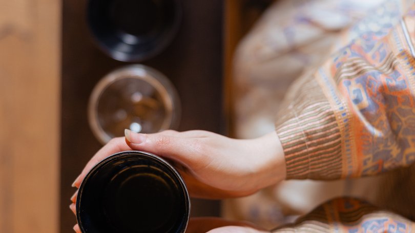 Escursioni da Moena e molto altro: il nostro programma Mani che tengono una tazza nera sopra un tavolo con bicchieri