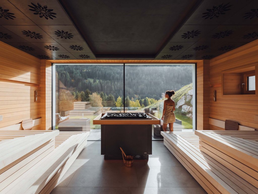 Soraga: dal lago alla piscina del Latemar Donna in asciugamano che guarda il paesaggio montano da una sauna moderna in legno
