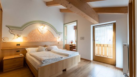Meteo, Moena, Soraga, Latemar: tutto nella nostra gallery Camera da letto con letto matrimoniale, soffitto con travi in legno e balcone