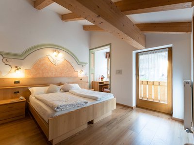 Hotel a 3 stelle superior a Soraga in Val di Fassa: camere & suites Camera da letto con letto matrimoniale, soffitto con travi in legno e balcone