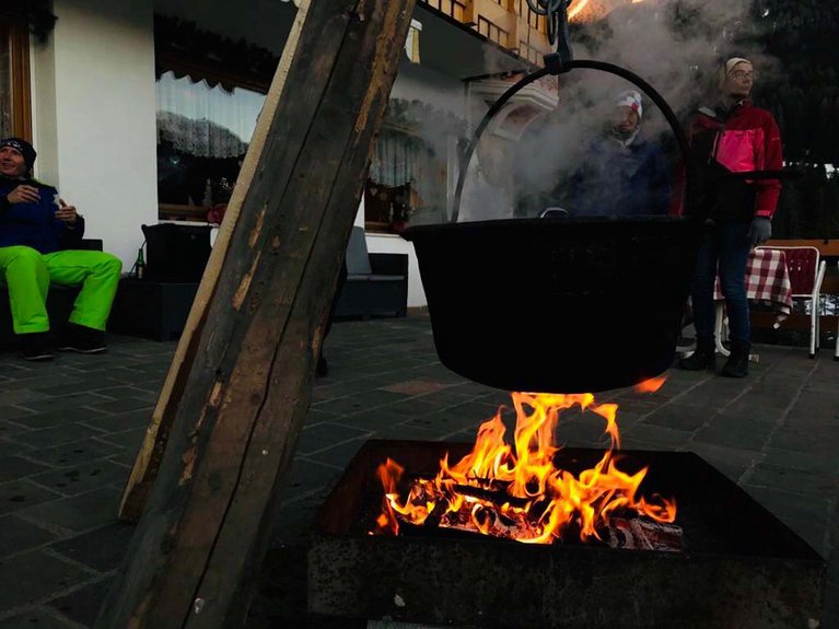 Dalla webcam il Latemar è bello, ma dal vivo è un sogno! Pentola sospesa sopra un fuoco acceso all'aperto con persone intorno