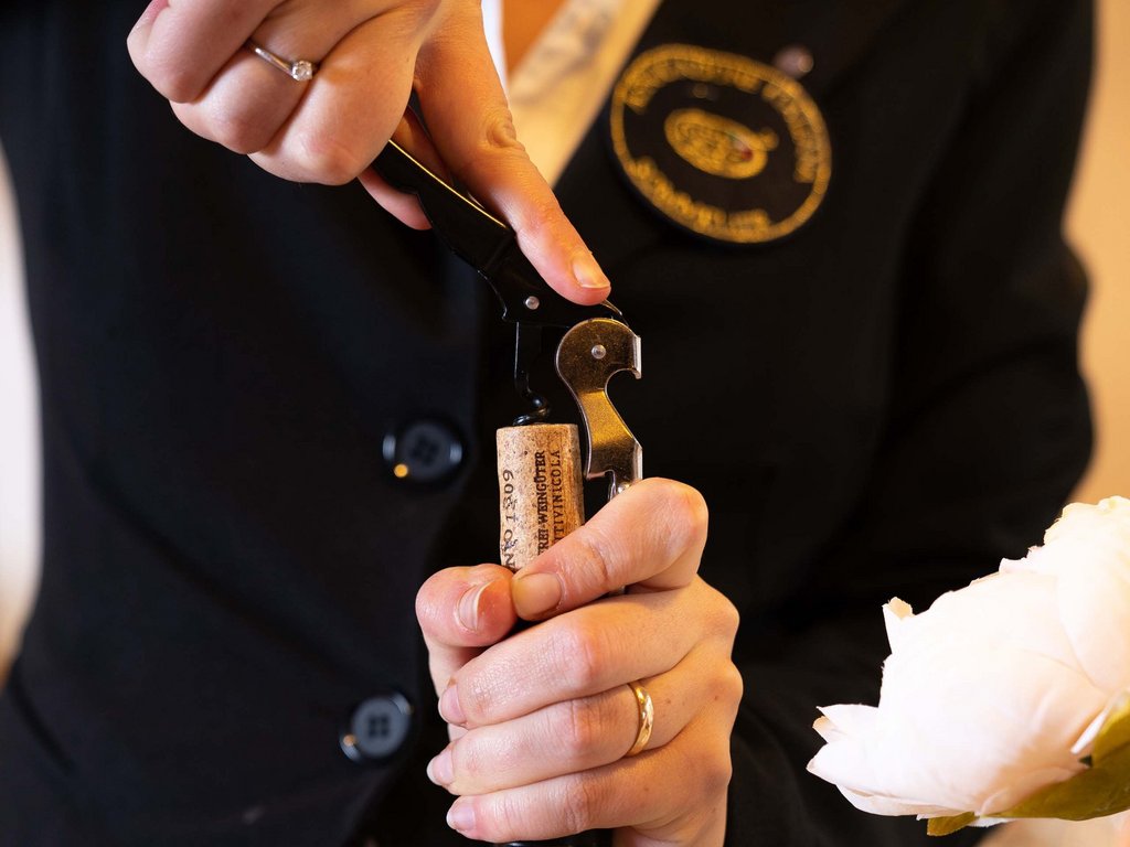 In Val di Fassa in inverno e in estate si brinda col vino! Persona che apre una bottiglia di vino con un cavatappi