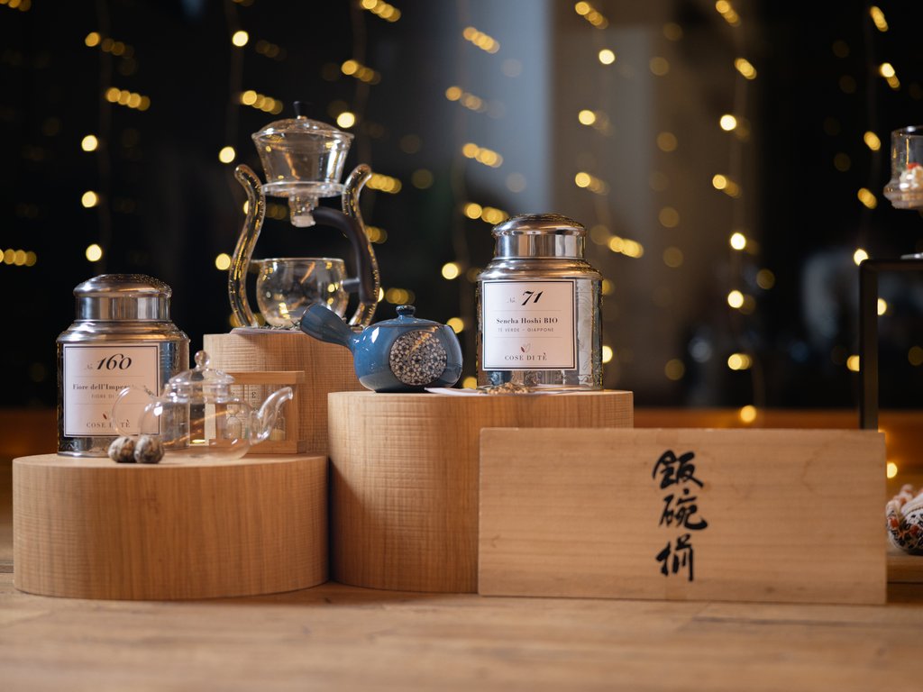 Val di Fassa e ciclabile: da ammirare dal cocktail & tea bar Barattoli di tè, teiere e accessori su espositori di legno con luci sfocate sullo sfondo