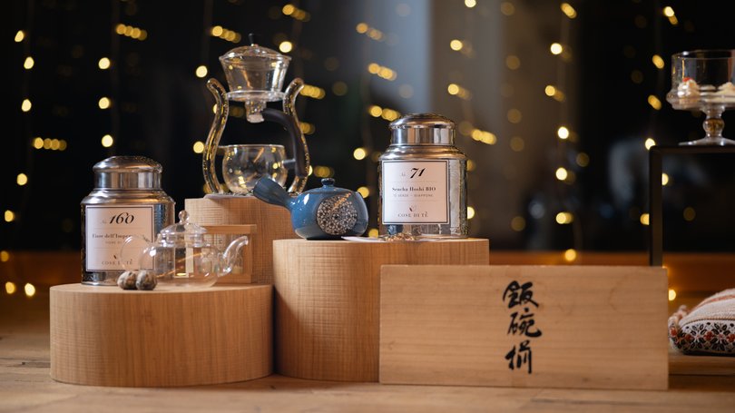 Escursioni da Moena e molto altro: il nostro programma Barattoli di tè, teiere e accessori su espositori di legno con luci sfocate sullo sfondo