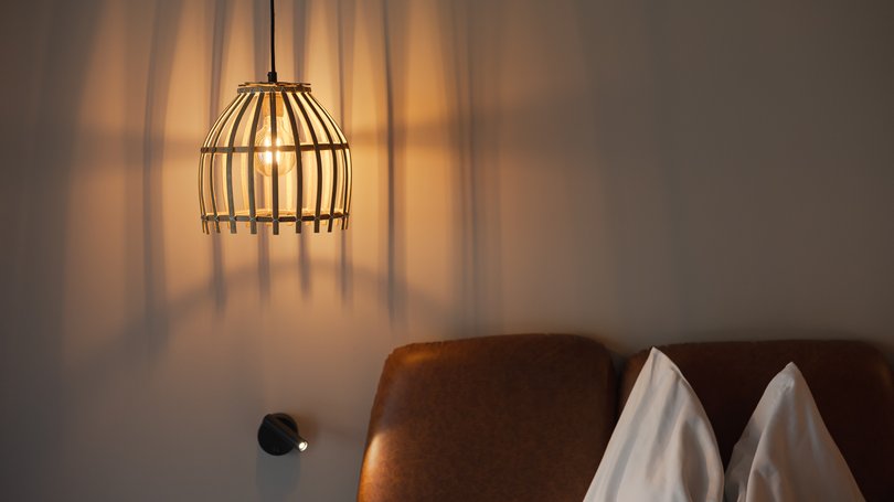 Moena, alberghi da sogno, panorama? C’è l’Hotel Latemar! Lampada a sospensione accesa sopra testata letto con cuscini bianchi