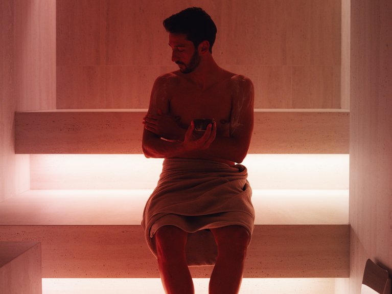 Il rituale dell’hammam al Latemar Hotel Uomo con asciugamano seduto in sauna illuminata con luce calda