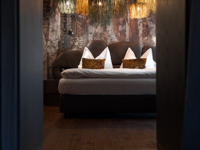 Hotel per disabili in Val di Fassa: il Latemar Camera da letto moderna con luci sospese decorative e un grande letto.