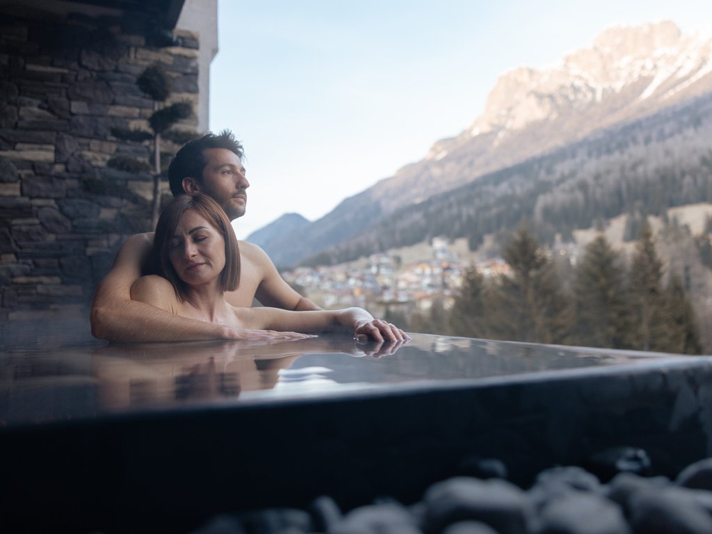 Soraga: dal lago alla piscina del Latemar Coppia rilassata in una vasca idromassaggio con vista sulle montagne