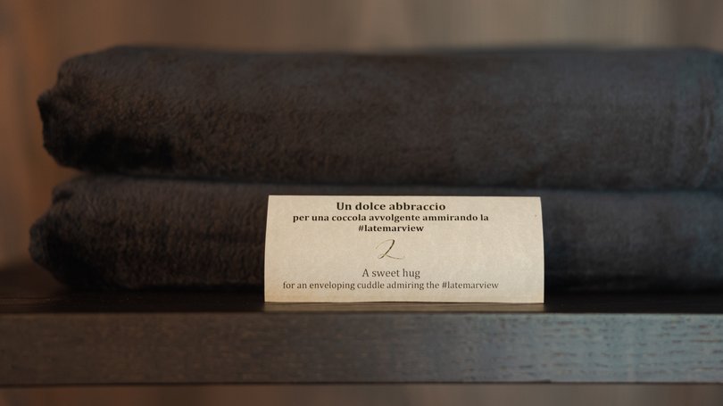 Moena, alberghi da sogno, panorama? C’è l’Hotel Latemar! Due asciugamani scuri piegati con un biglietto con testo in italiano e inglese