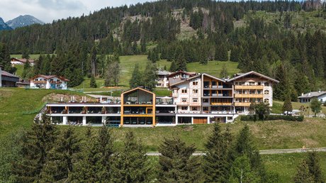 Meteo, Moena, Soraga, Latemar: tutto nella nostra gallery Hotel moderno in montagna circondato da alberi e colline verdi sotto un cielo nuvoloso