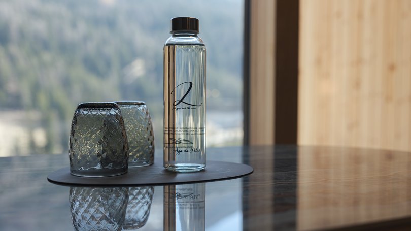 Moena, alberghi da sogno, panorama? C’è l’Hotel Latemar! Bottiglia d'acqua e due bicchieri rovesciati su un tavolo con vista montagna