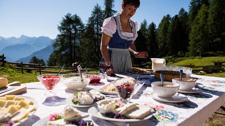 Meteo, Moena, Soraga, Latemar: tutto nella nostra gallery Donna in abito tradizionale prepara cibo su tavolo all'aperto in montagna