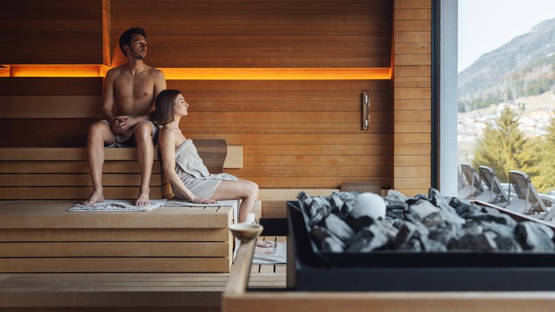 Escursioni da Moena e molto altro: il nostro programma Coppia rilassata in sauna con vista su montagne e sedie a sdraio