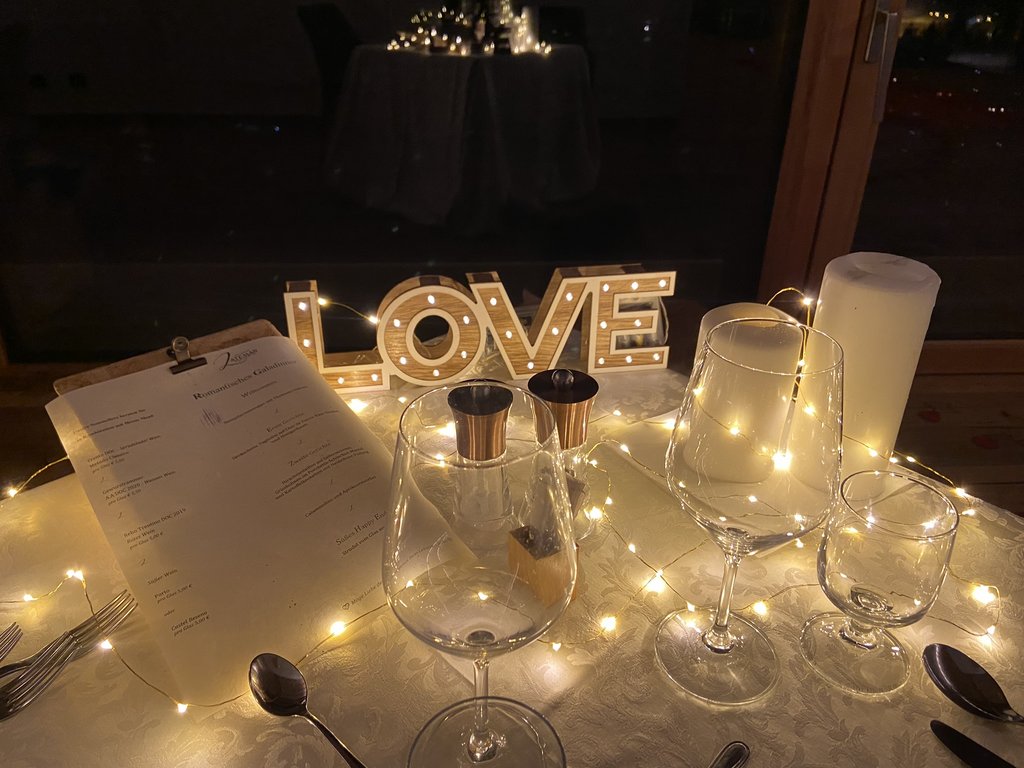 On the cycle track, from Moena to your romantic oasis Romantic table setting with glasses, menu, fairy lights, and illuminated LOVE sign