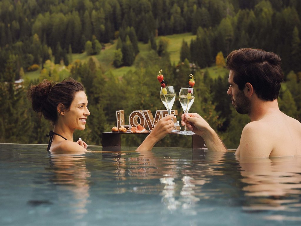 On the cycle track, from Moena to your romantic oasis Couple toasting in pool with mountain view