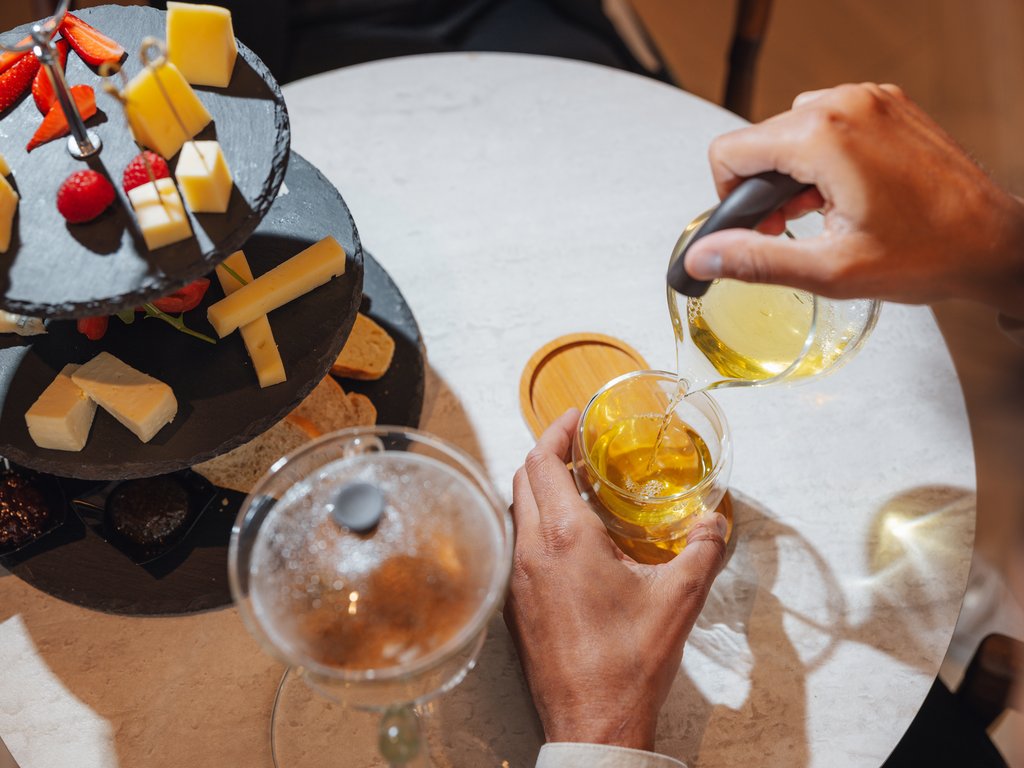 On the cycle track, from Moena to your romantic oasis Hand pouring tea and platter with cheese and strawberries on white table