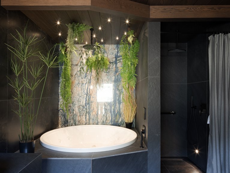 Hotel Latemar con vista sulle Dolomiti Vasca idromassaggio tonda con piante verdi in bagno moderno con pareti scure