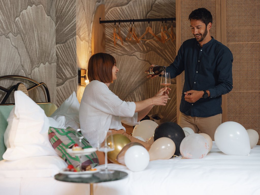 On the cycle track, from Moena to your romantic oasis Couple toasting with wine glass in a room decorated with balloons