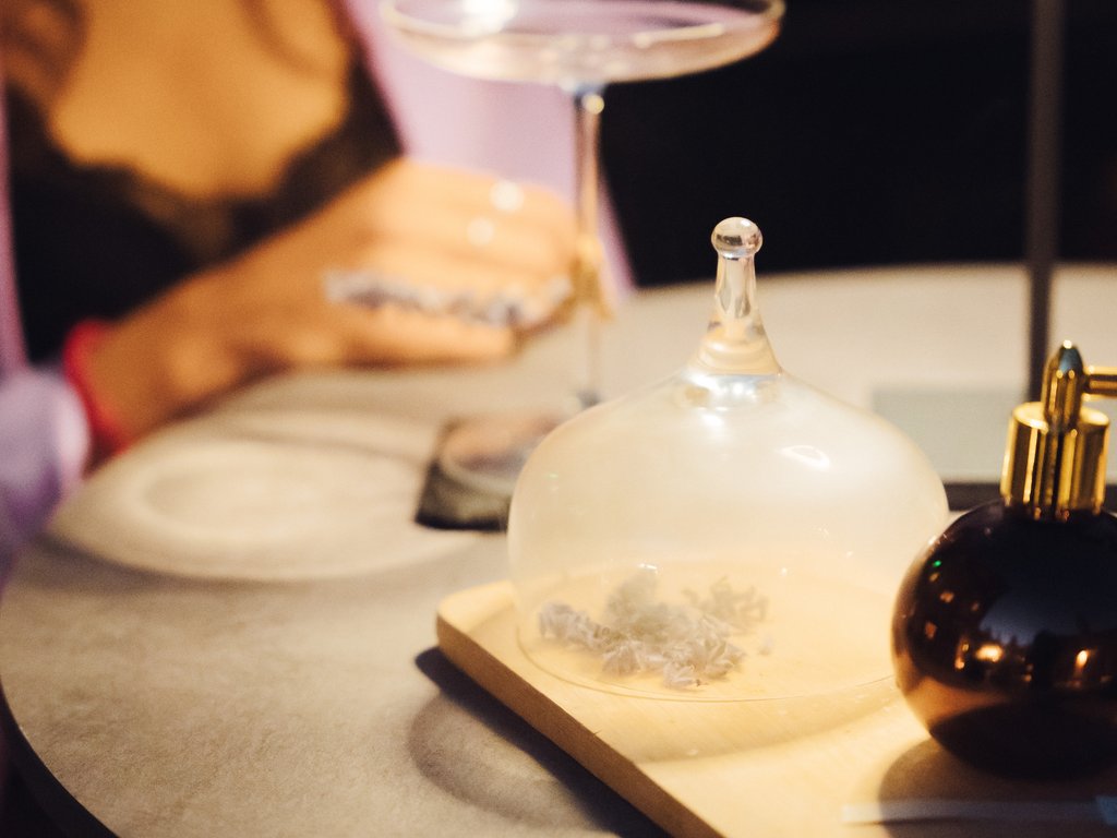 On the cycle track, from Moena to your romantic oasis Table with glass cloche, drink, and blurred person in background