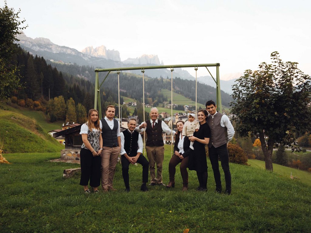 Hotel in Soraga: family passion Family group standing by a swing with mountains in the background