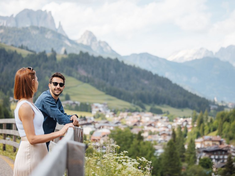 Hotel Latemar con vista sulle Dolomiti Coppia che ammira un paesaggio montano con villaggio e alberi