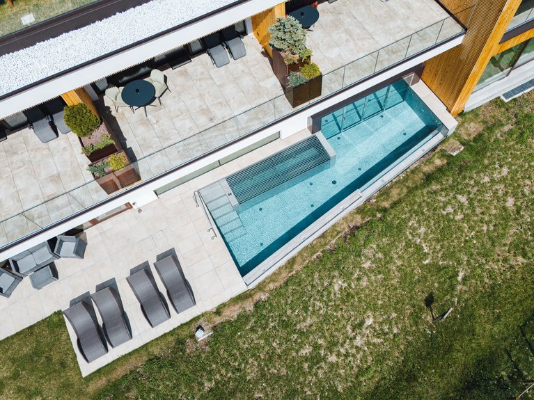 Hotel Latemar con vista sulle Dolomiti Terrazza moderna con lettini e piscina vicino a un edificio con struttura in legno.