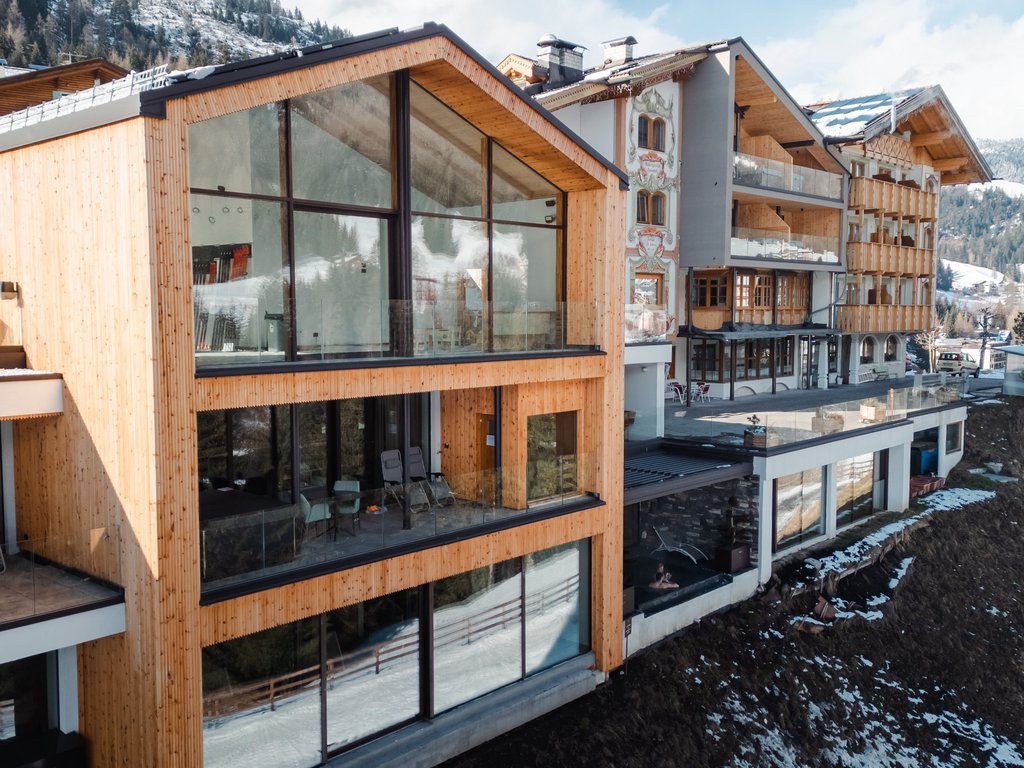 Hotel Latemar con vista sulle Dolomiti Edificio moderno in legno con grandi finestre su pendio innevato in montagna