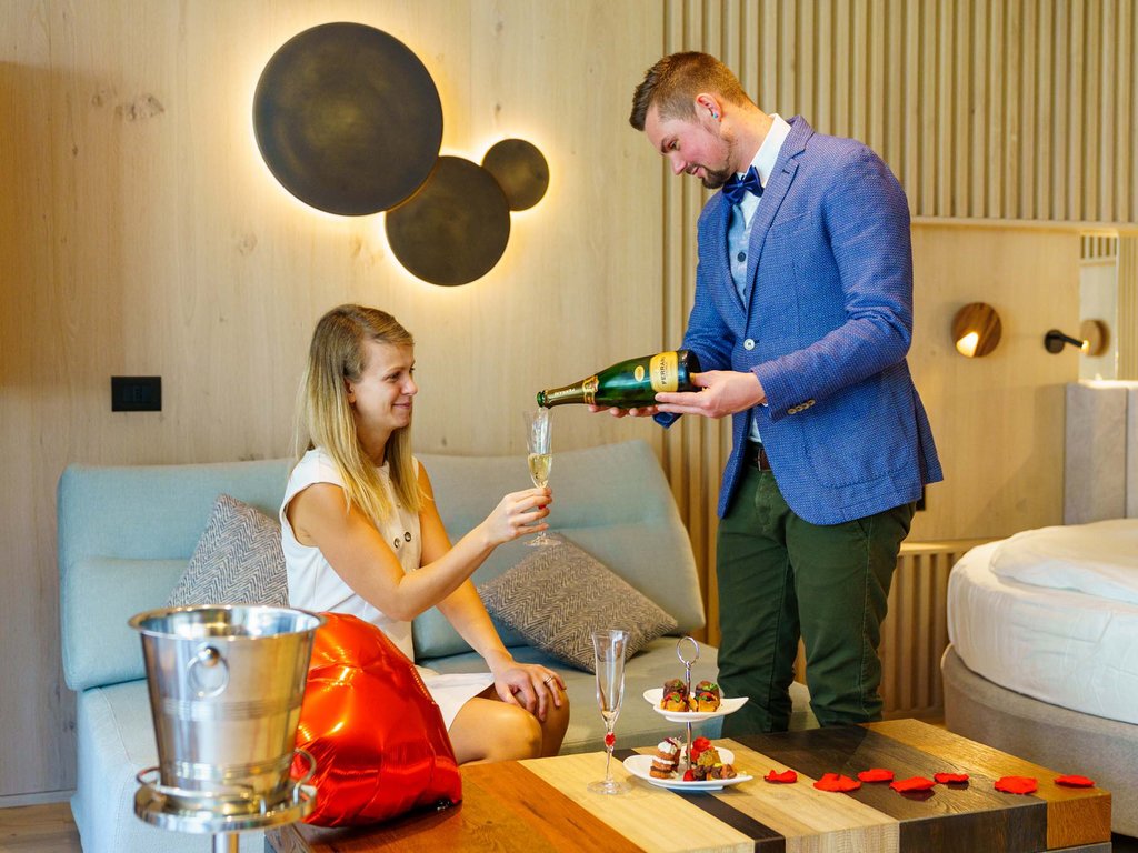 On the cycle track, from Moena to your romantic oasis Couple toasting with champagne in an elegant room with romantic decorations