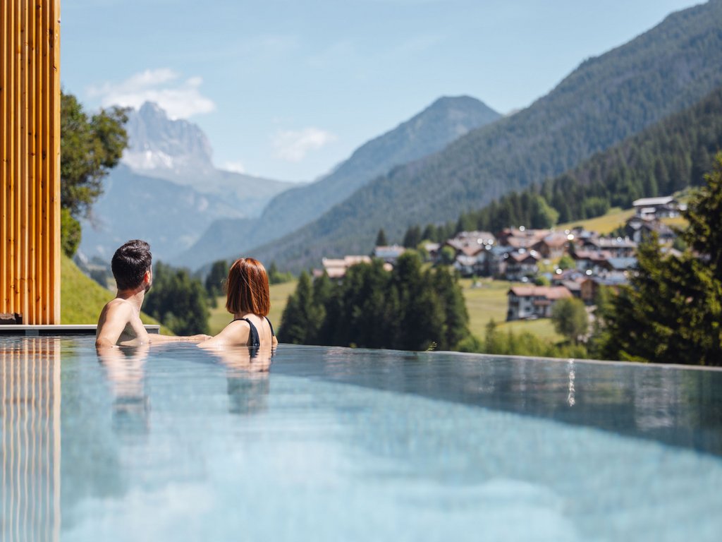 Hotel Latemar con vista sulle Dolomiti Coppia in piscina a sfioro con vista sulle montagne e un villaggio