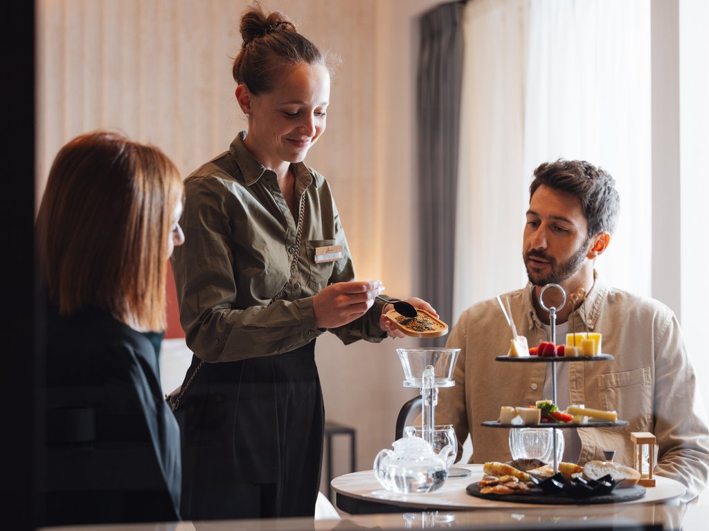 On the cycle track, from Moena to your romantic oasis Couple at table with waitress showing a package of tea or spices