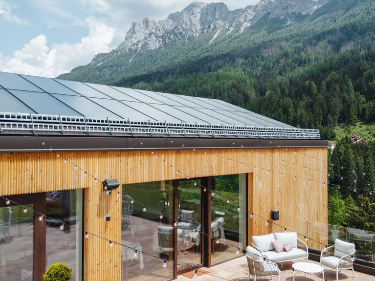 Hotel Latemar con vista sulle Dolomiti Terrazza con sedute moderne e luci a fili davanti a edificio in legno con montagne sullo sfondo