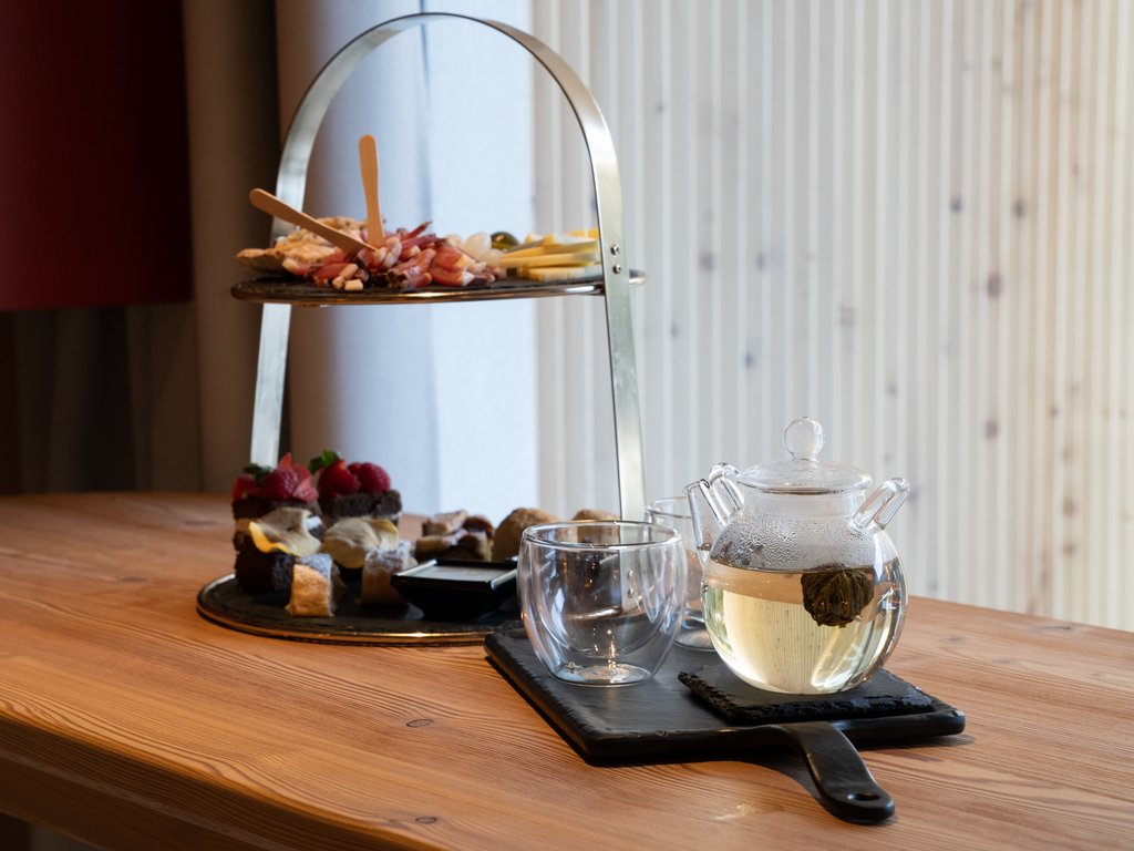 On the cycle track, from Moena to your romantic oasis Glass teapot with tea, tray, and assorted sweets on a two-tier serving stand