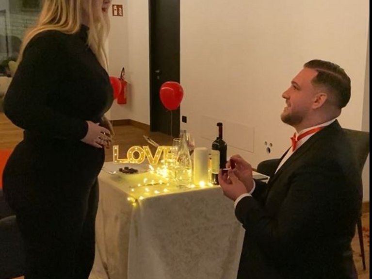 On the cycle track, from Moena to your romantic oasis Man kneeling proposing to woman by decorated table with lights and rose petals