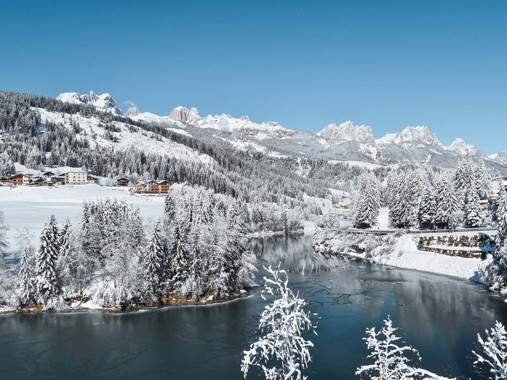 Hotel Latemar con vista sulle Dolomiti Paesaggio innevato con alberi, fiume e montagne sullo sfondo