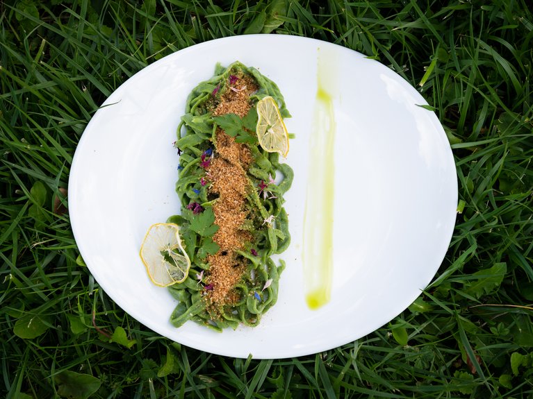 Hotel Latemar con vista sulle Dolomiti Piatto di pasta verde con briciole e fette di limone su un prato verde