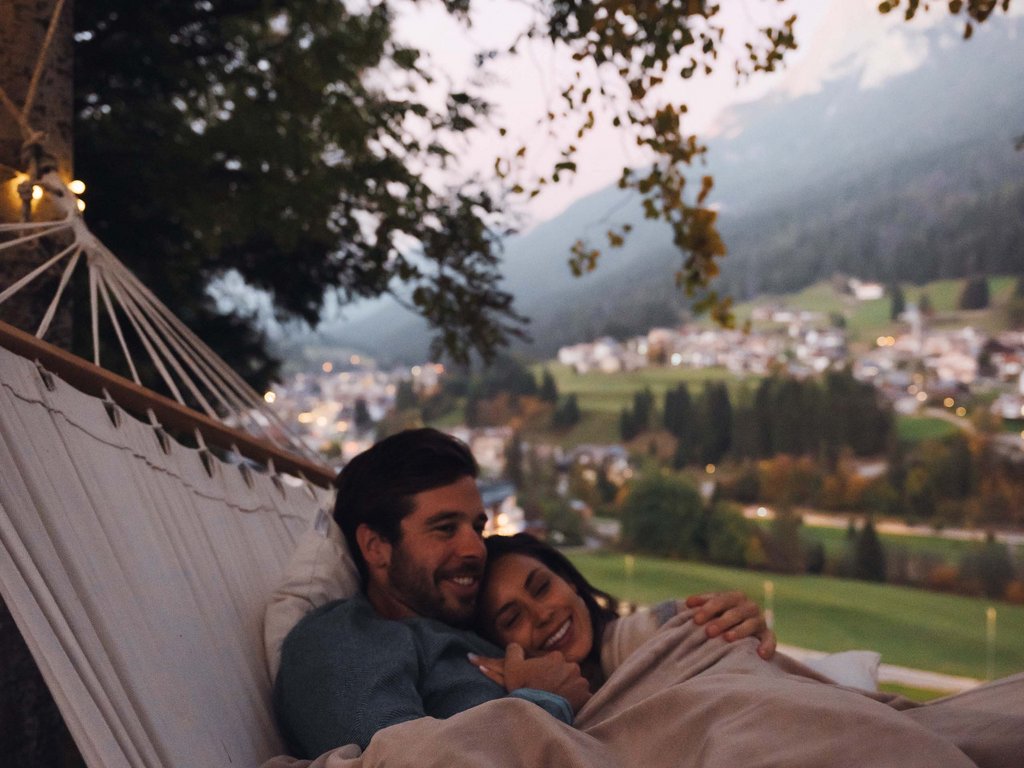 On the cycle track, from Moena to your romantic oasis Couple cuddling in a hammock with panoramic sunset view